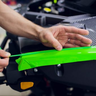 Car wrapping specialists wrapping a vehicle with grey vinyl film or foil